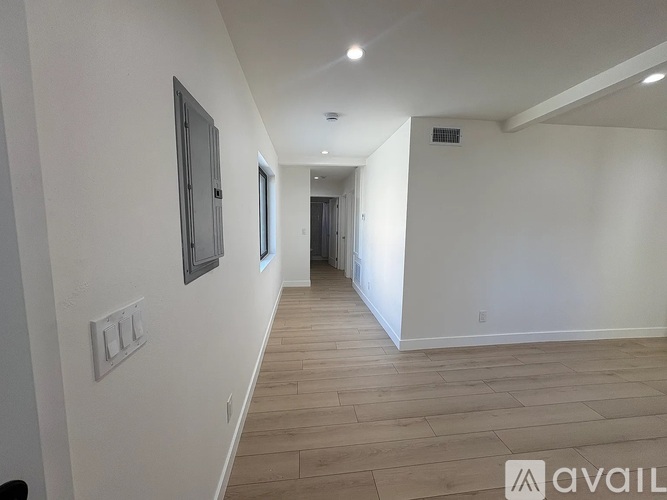 A long hallway with wood floors and white walls.