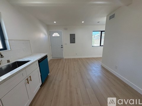 A kitchen with white cabinets and a blue trash can.