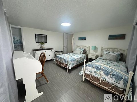 A bedroom with two beds and a dresser.