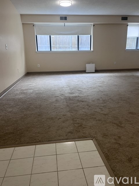 A room with carpeted floor and a window with blinds.