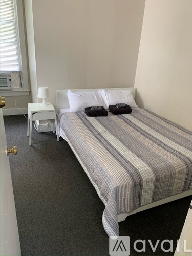 A bedroom with a bed, nightstand, and window.
