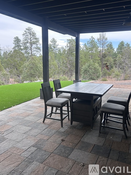 A patio with a table and chairs overlooking a grassy area.