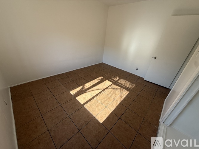 A room with brown tiles and a window letting in sunlight.