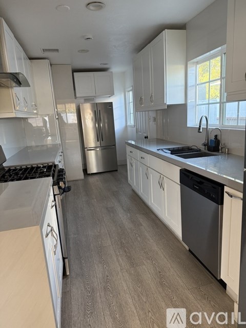 A kitchen with white cabinets and a stainless steel refrigerator.
