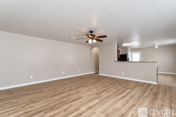 A spacious room with wooden flooring and a ceiling fan.