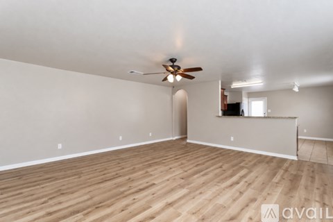 A spacious room with wooden flooring and a ceiling fan.