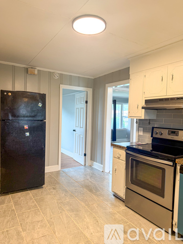 A kitchen with a black fridge and a black stove top oven.