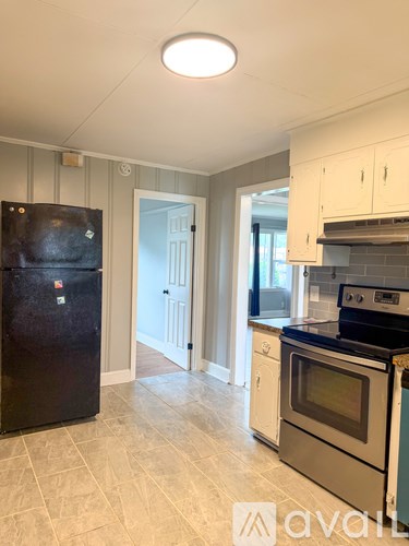 A kitchen with a black fridge and a black stove top oven.