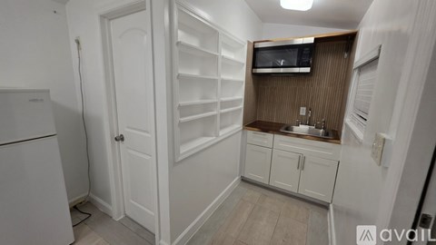 A small kitchen with a white refrigerator and a white door.