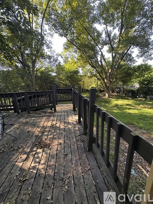 A wooden bridge in a park with trees in the background.