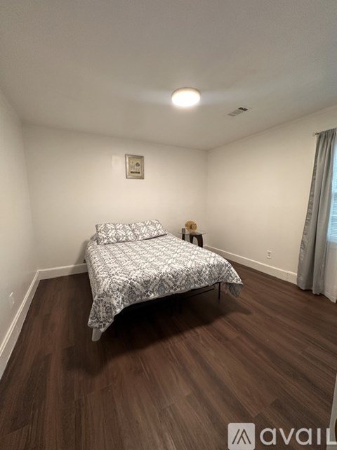 A bedroom with a bed and wooden flooring.