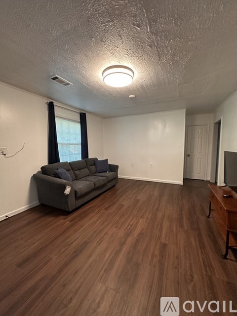 A living room with a grey couch and wooden flooring.