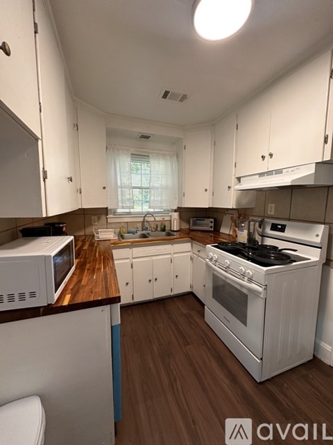 A kitchen with white cabinets and a wooden countertop.
