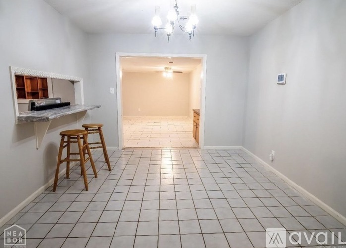 A room with a white tile floor and a white wall with a shelf and two stools.