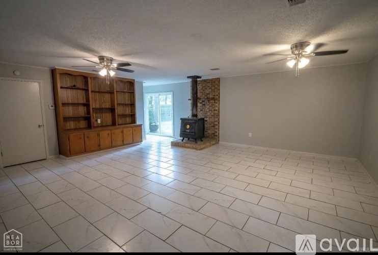 A spacious living room with a fireplace and a bookshelf.