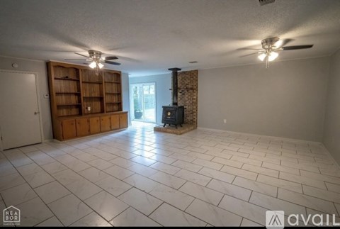 A spacious living room with a fireplace and a bookshelf.
