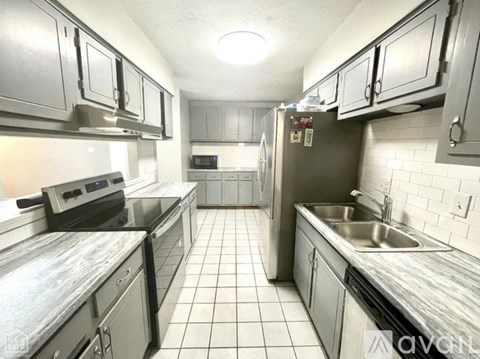 A kitchen with white tiled floors and stainless steel appliances.