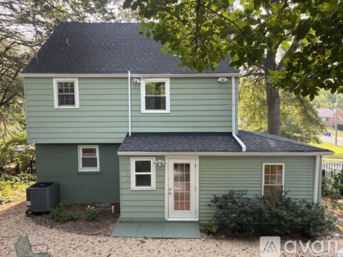 A two-story house with a grey roof and a green exterior.