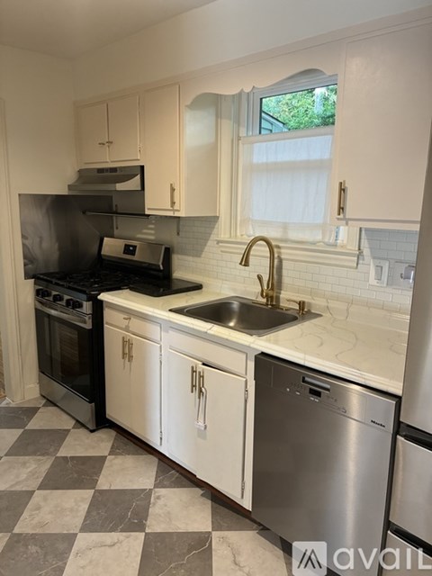 A kitchen with a checkered floor and white cabinets.