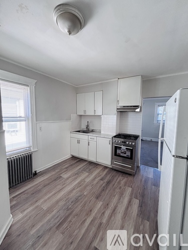 A kitchen with white cabinets and a wooden floor.