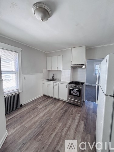 A kitchen with white cabinets and a wooden floor.