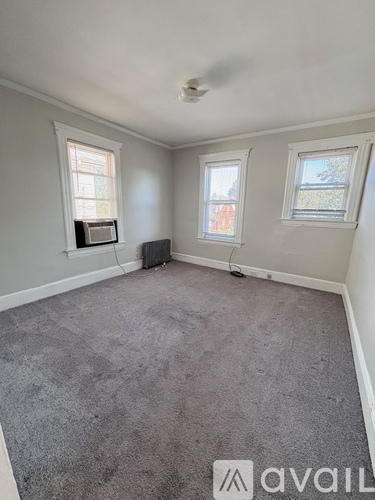 A room with grey carpet and two windows.
