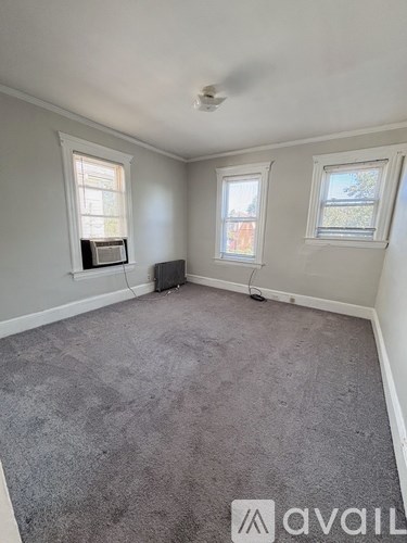 A room with grey carpet and two windows.