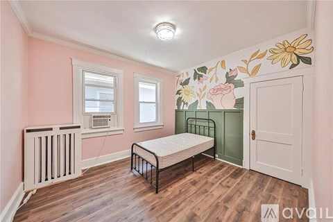 A bedroom with a bed, a window, and a wall mural.
