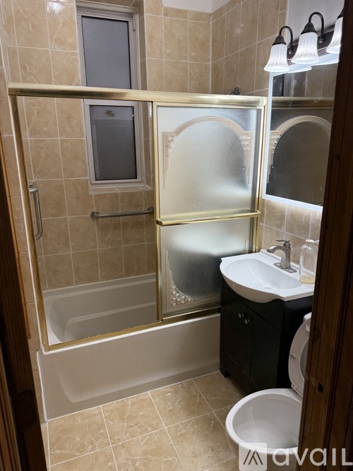 A bathroom with a tiled wall and a glass shower door.