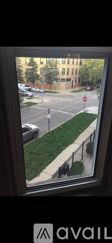 A view from a window looking out at a street with cars and buildings.