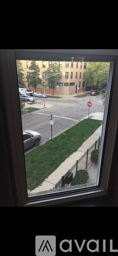 A view from a window looking out at a street with cars and buildings.