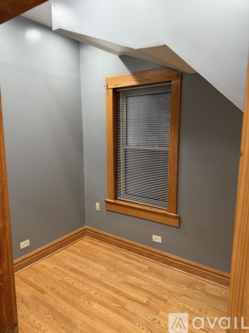 A room with a window and wooden flooring.