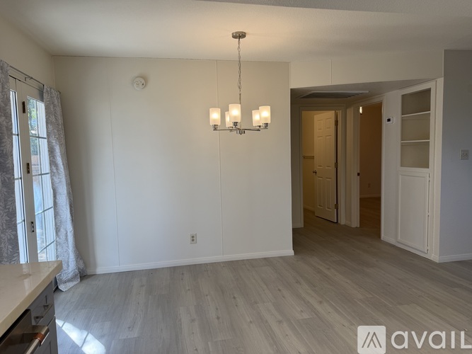 A well-lit room with a chandelier and a kitchen counter.