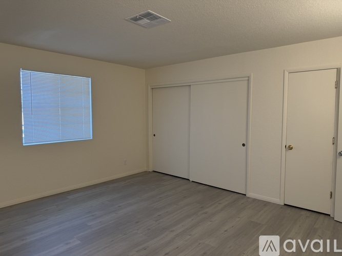A room with a window, two closets, and a door.