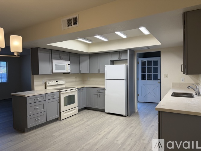A modern kitchen with a white refrigerator and wooden flooring.