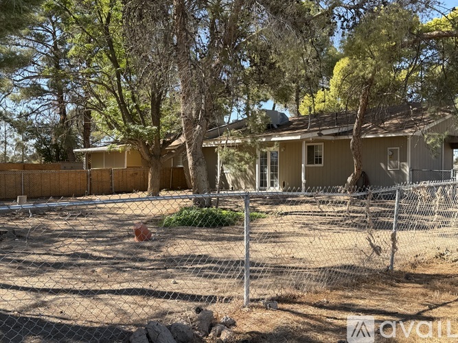 A house with a fence and trees in the background.