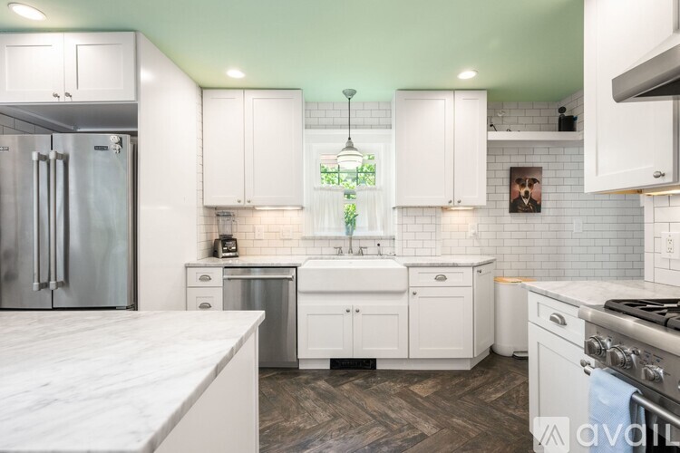 A kitchen with white cabinets and a marble countertop.