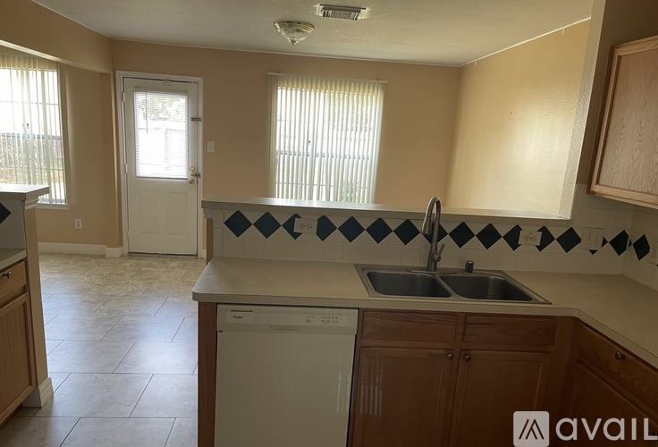 A kitchen with a white dishwasher and a checkered backsplash.