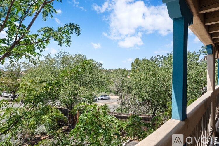 A balcony overlooks a parking lot and trees.