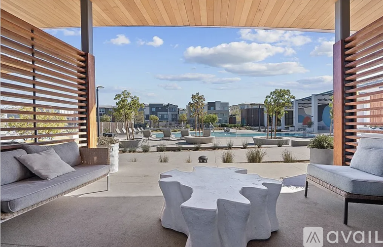 A patio with a white table and chairs is shown with a view of a pool and buildings in the distance.