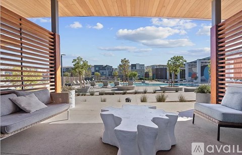 A patio with a white table and chairs is shown with a view of a pool and buildings in the distance.