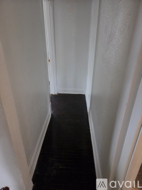 A hallway with white walls and black flooring.