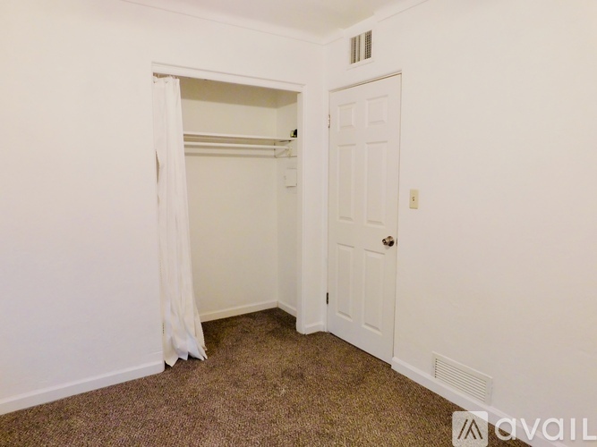 A bedroom with a white door and a white curtain.