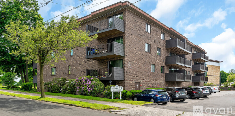 Apartment building with balconies and cars parked in front.