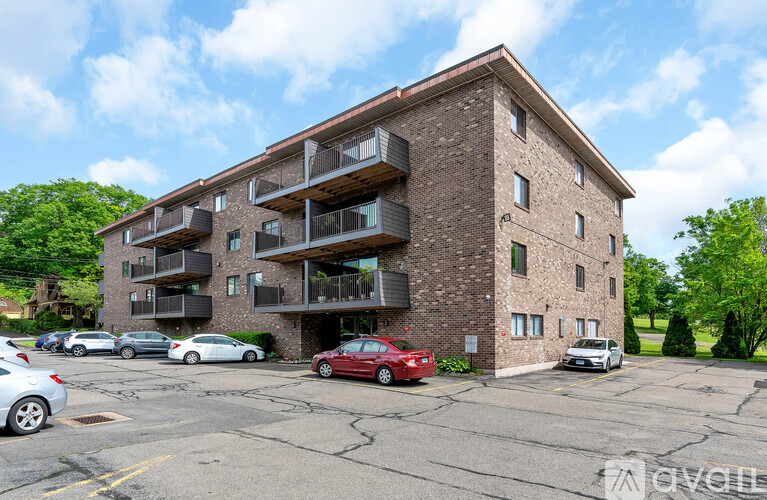 A red car is parked in front of a brick apartment building.