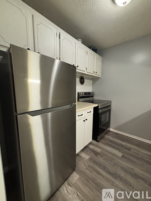A kitchen with a stainless steel refrigerator and white cabinets.
