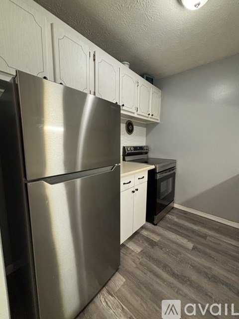 A kitchen with a stainless steel refrigerator and white cabinets.