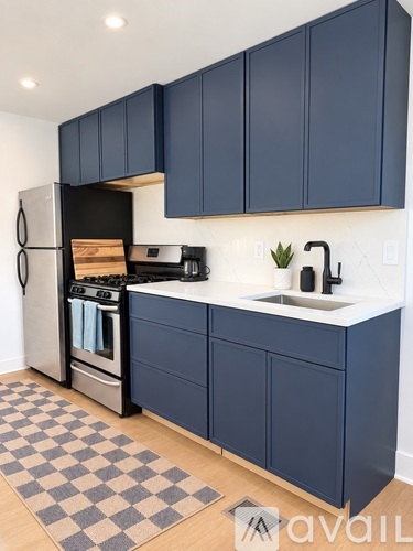 A kitchen with dark blue cabinets and a checkered rug.