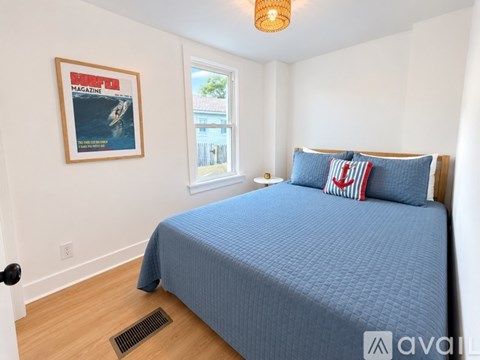 A bedroom with a blue bedspread and a framed picture of a magazine on the wall.
