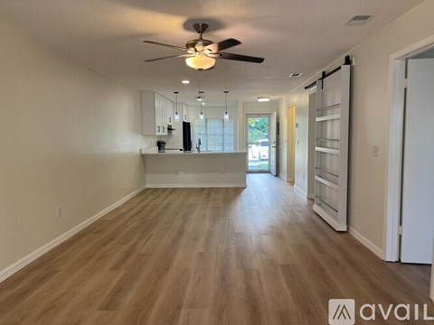 A spacious room with wooden flooring and a ceiling fan.